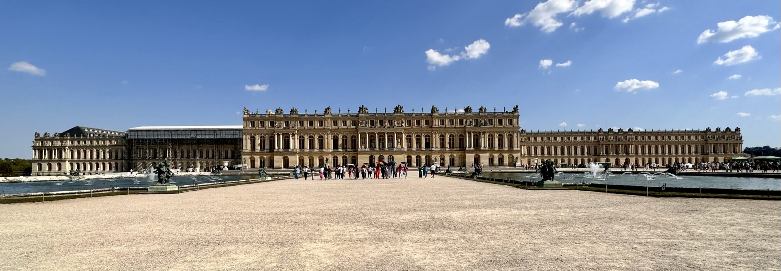 La façade du château de Versailles depuis les jardins, sous un ciel bleu