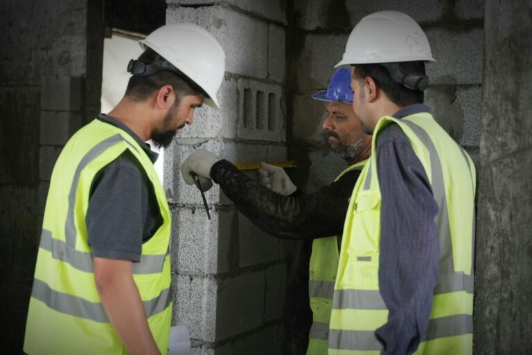 Deux professionnels équipés examinent un mur sur un chantier