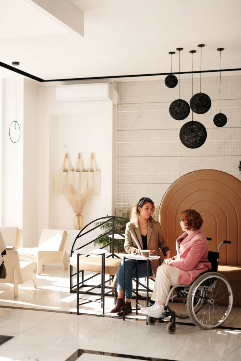 Deux femmes échangent autour d’une table, dont une en fauteuil roulant
