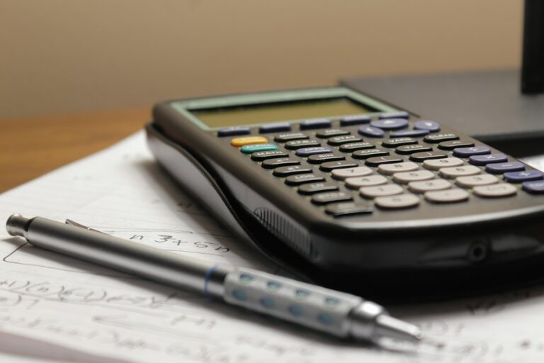 Calculatrice et stylo posés sur des notes de calcul
