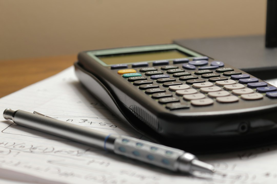 Calculatrice et stylo posés sur des notes de calcul